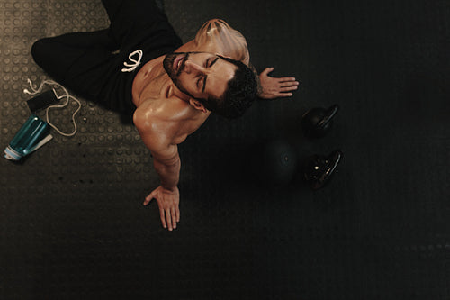 Exhausted man relaxing on gym floor after workout