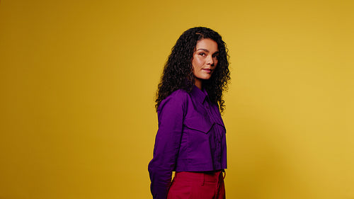 Confident young woman posing and smiling in studio with vibrant colors