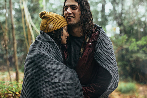 Couple wrapped in blanket under the rain 