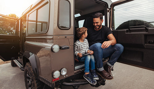 Happy father and son sitting at the back of the car