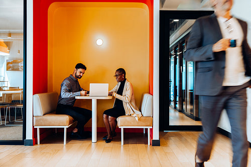 Two professionals working at a table in an office lounge area