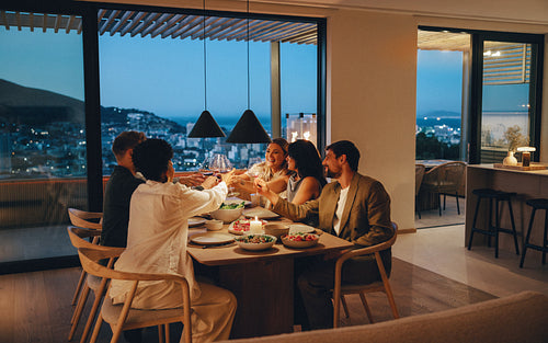 Friends enjoying dinner together at home with a scenic evening backdrop
