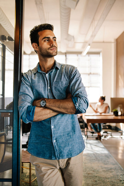Young man standing at door while colleagues in background
