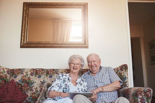 Smiling senior couple with a digital tablet at home