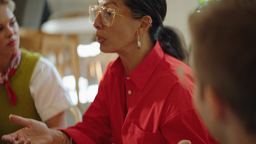Colleague watches as woman presents during a team meeting in a cafe workspace