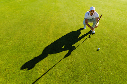 Golf player aiming shot with club on course