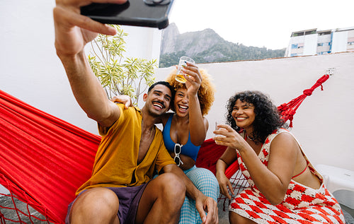 razilian friends enjoying rooftop drinks and taking a lively selfie