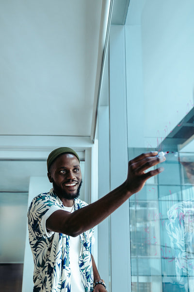 African-American businessman writing on a whiteboard in a futuristic office setting
