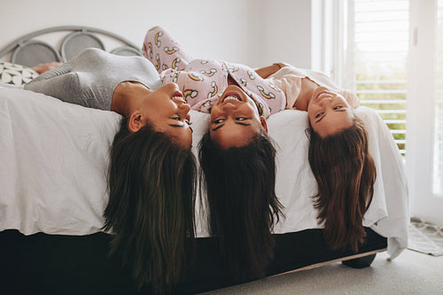 Girls lying on bed having fun at a sleepover