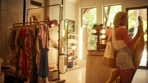 Woman trying on a yellow dress in a luxurious resort boutique