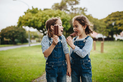 Twin sisters enjoying eating candy icecream 