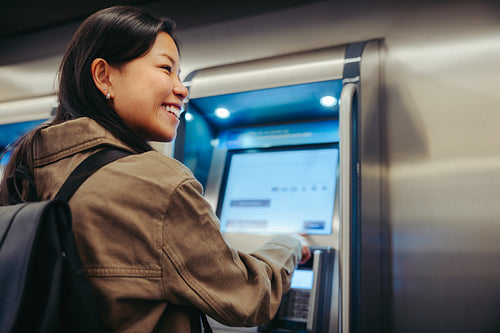 Smiling commuter buying a ticket at transit kiosk