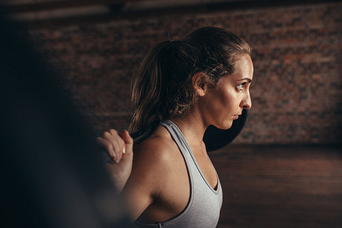 Healthy young woman at gym exercising with barbell