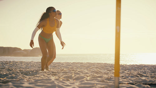Slow-motion shot of two professional athletes playing beach volleyball at sunset