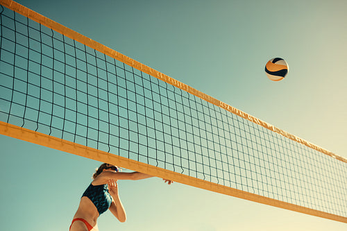 Female athlete soars through air in beach volleyball championship game