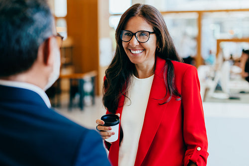 Professional woman smiling while conversing with colleague in business environment