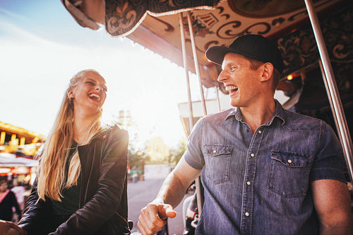 Laughing young friends riding on carousel