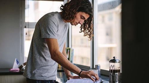 Student standing in kitchen and studying