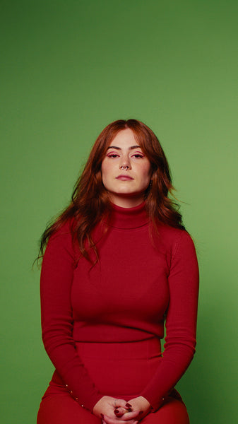 Smiling redhead woman in red dress against green screen