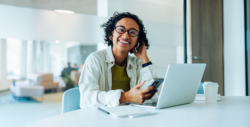Smiling woman at desk with laptop and phone