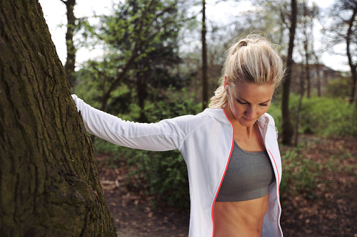Beautiful young woman resting after jogging in a park