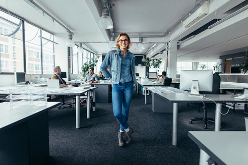 Young businesswoman standing in office with colleagues