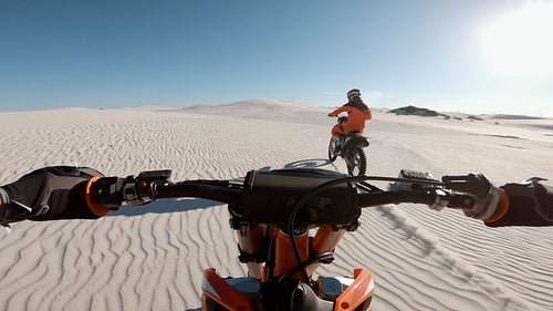 Motorcyclist riding behind his competitor over sand dunes