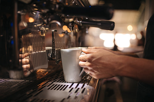 Female cafe worker preparing coffee in machine