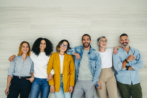 Happy businesspeople standing against a wall in an office