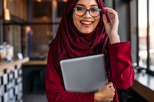 Woman in hijab at coffee shop with laptop