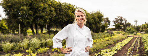 Cheerful young chef smiling at the camera on a farm