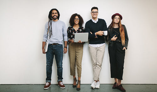 Business colleagues standing in office holding laptops and tablet