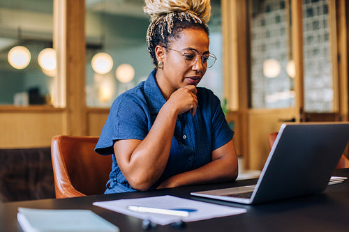 Woman attentively working on her laptop in a bright office environment