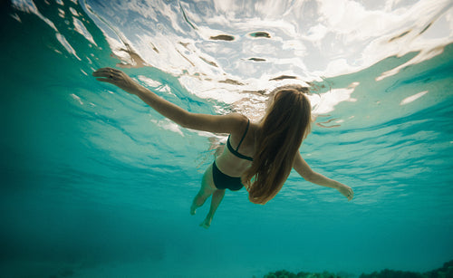 Woman swimming underwater in clear turquoise ocean water in a serene environment