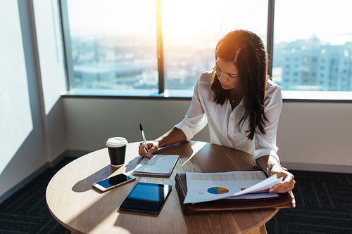 Businesswoman sitting at round table doing office work.