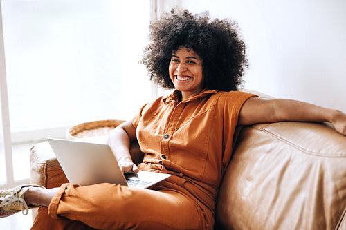 Cheerful young businesswoman smiling while sitting on a couch