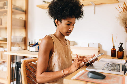 Jewelry designer using phone and laptop