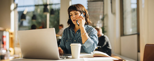 Businesswoman talking on cell phone in coworking space