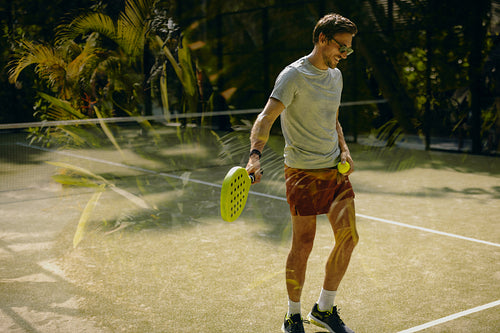 Padel player practicing on court at a tropical holiday resort