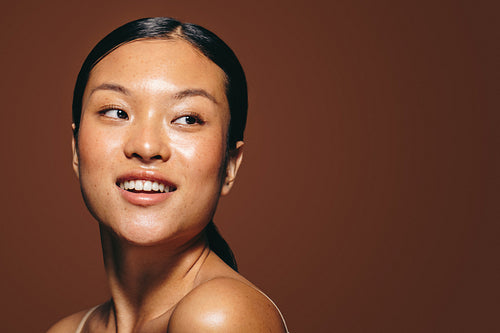 Radiant in the studio, a young woman in her 20’s stands with flawless skin