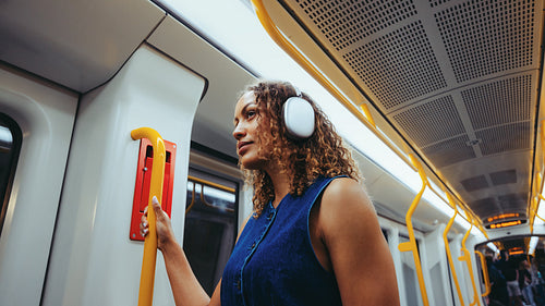 Woman wearing headphones travels by metro on city commute
