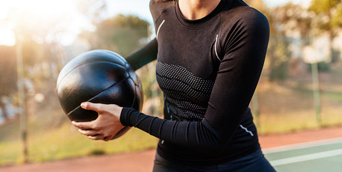 Sportswoman exercising with fitness ball on tennis court