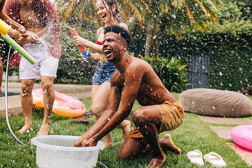 Friends having water fight in backyard