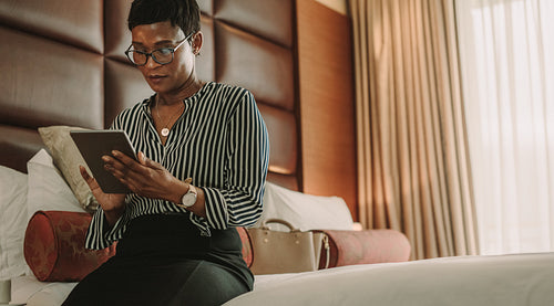 Businesswoman sitting on bed using digital tablet