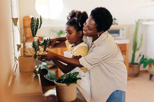 Mother teaching daughter the art of indoor plant care with a spray bottle