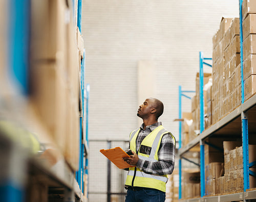 Young logistics worker taking stock in a modern warehouse