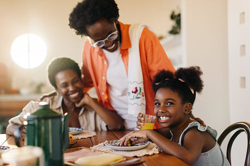 Brazilian dad serving his wife and daughter breakfast at the table