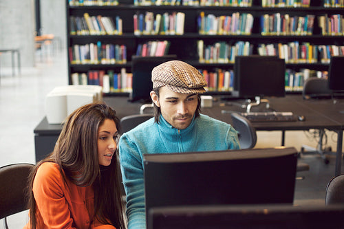 Students finding information for study on computer in library