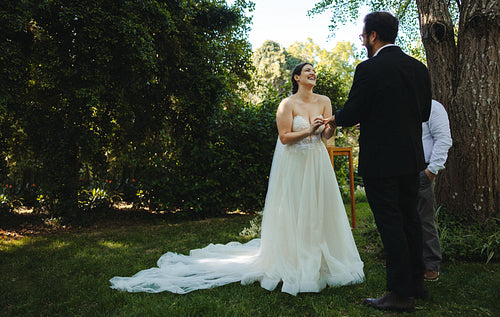 Bride and groom exchanging rings in beautiful outdoor wedding ceremony