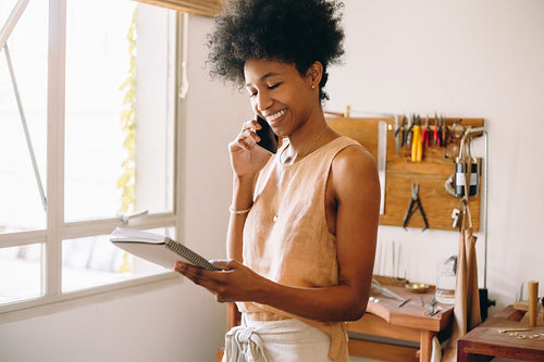 Happy jeweler on phone in studio